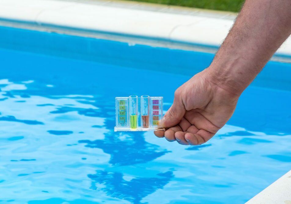 Tester for pool in a hand against the background of the swimming pool.